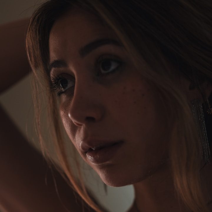 Porträt einer Frau mit nachdenklichem Ausdruck und leichtem Lichtspiel im Hintergrund.